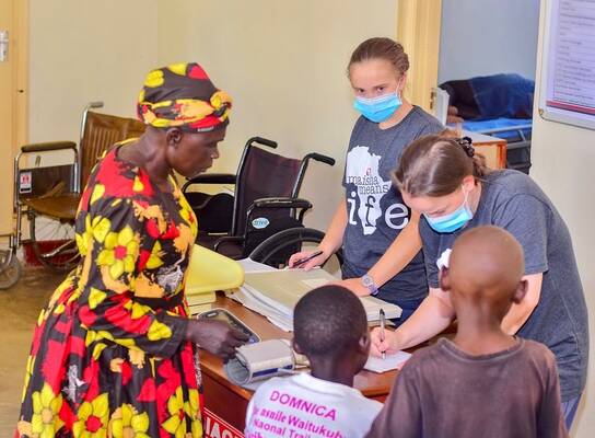 Volunteers and local staff documenting patient information inside the Maisha clinic during a medical care day