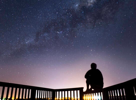 Student poses beneath star filled sky.