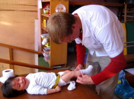 volunteer changing toddler's socks