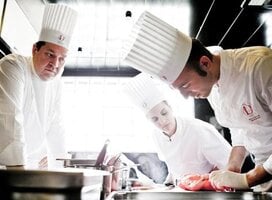 chefs leaning over a cooking station