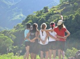 Group of volunteers hiking and hugging in mountain scenery
