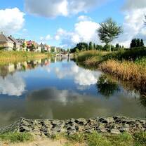 still river with refelection of blue sky with clouds and houses alongside
