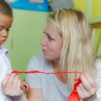 Volunteer assisting a young boy with his ribbon in Ecuador