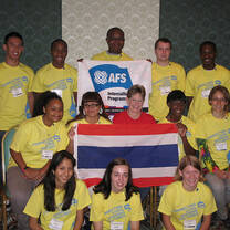 Group of students in yellow shirts holding AFS sign and flag of Thailand