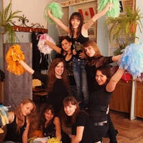 Group of girls wearing black shirts holding pom poms with arms raised