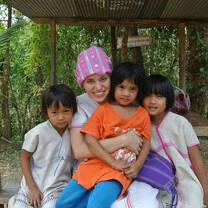 Volunteer with pink hat posing with 3 children in Thailand