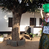 woman holding green bucket on head in Ghana