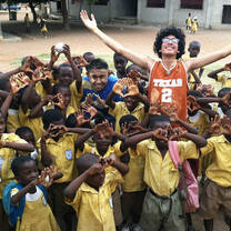 Group of school children and high school volunteer with arms raised
