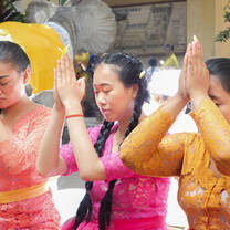 Volunteers Cindy and Linh with local staff member Tutik praying during a local ceremony.