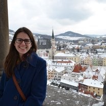 girl in blue jacket smiling with snowy city backdrop