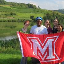 student group with Miami flag next to river