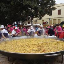 giant pot of paella with people standing around it cooking