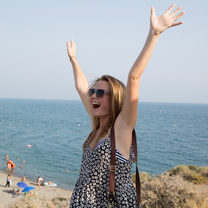 Girl with arms reaching towards the sky on beach on Spain