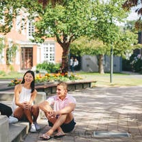 Two students sitting outside on a sunny day