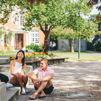 Two students sitting outside on a sunny day