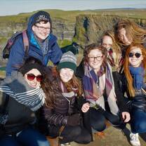 group of girls smiling in front of green hills
