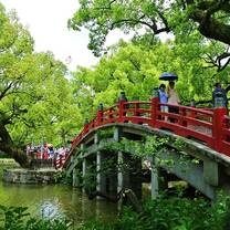 red bridge over a river with green trees