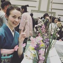 girl holding up peace sign next to flowers