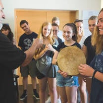 LITA students in a traditional music workshop; one student is holding a tamborine as the instructor teaches her how to use it