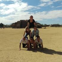 five people doing a human pyramid on the beach 
