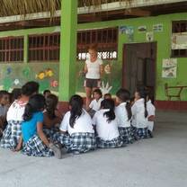 kids sitting in a circle on the ground around a teacher
