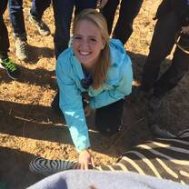 Veterinary experience participant smiles next to a zebra that they have darted