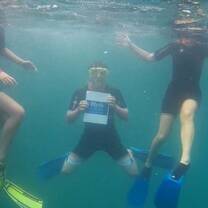 students holding up Blyth Academy Logo while scuba diving