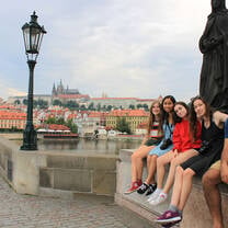students sitting on bridge in Prague