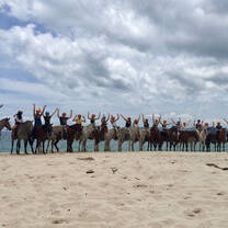 students riding horses on the beach