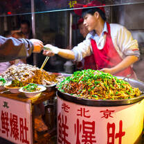 Wangfujing Snack Street at night. Chinese chef selling Ancient Beijing Soiled Pork Tripe. Located in Beijing, China.