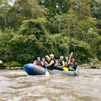 Students white water rafting down a murky river in the jungle near Baños