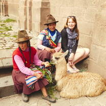 Posing with local women and a llama in Cusco Peru