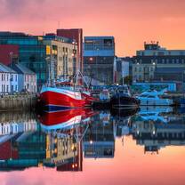 Galway Ireland, bright colored buildings on wharf at sunset with boats floating in the water