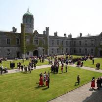 NUI Galway historical buildings with courtyard and masters students walking through on the grass fields