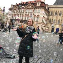 girl standing in the middle of Old Town Square surrounded by bubbles