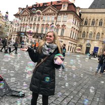 girl standing in the middle of Old Town Square surrounded by bubbles