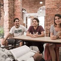 three students learning from instructor in brick building