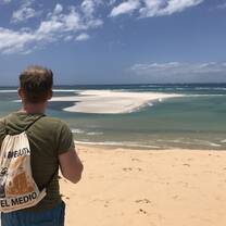 man standing looking out over beach and ocean 