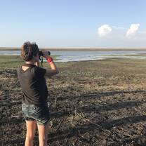woman using binoculars looking out over field