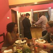 people in kitchen cooking and sitting at table eating