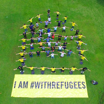 People on grass with protest sign arms out wide