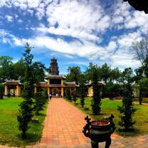 brick path leading to old building with green grass and bright blue sky
