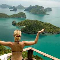 girl in yoga pose looking out over ocean and island