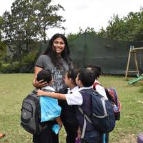 woman smiling with school kids hugging her