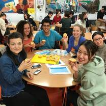 Young people each holding a small pie round the table.