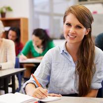 Girl holding pen inside a classroom.