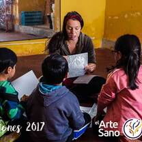 three kids and a woman sitting on the floor while chatting