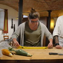 woman wearing glasses rolling dough for pasta