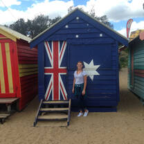 girl standing in front of small house painted with Australian flag on it
