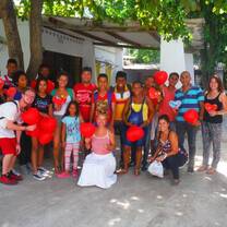 men, women and children holding red heart shaped balloons